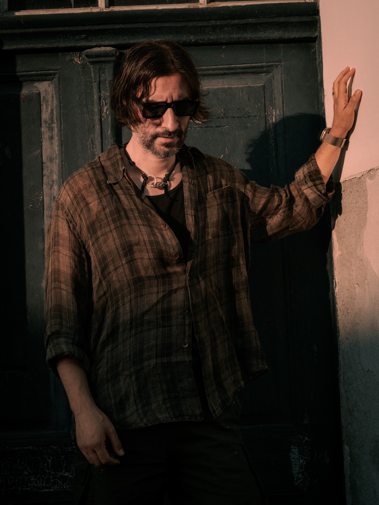 Portrait in a plaid shirt against a pink wall and dark green door