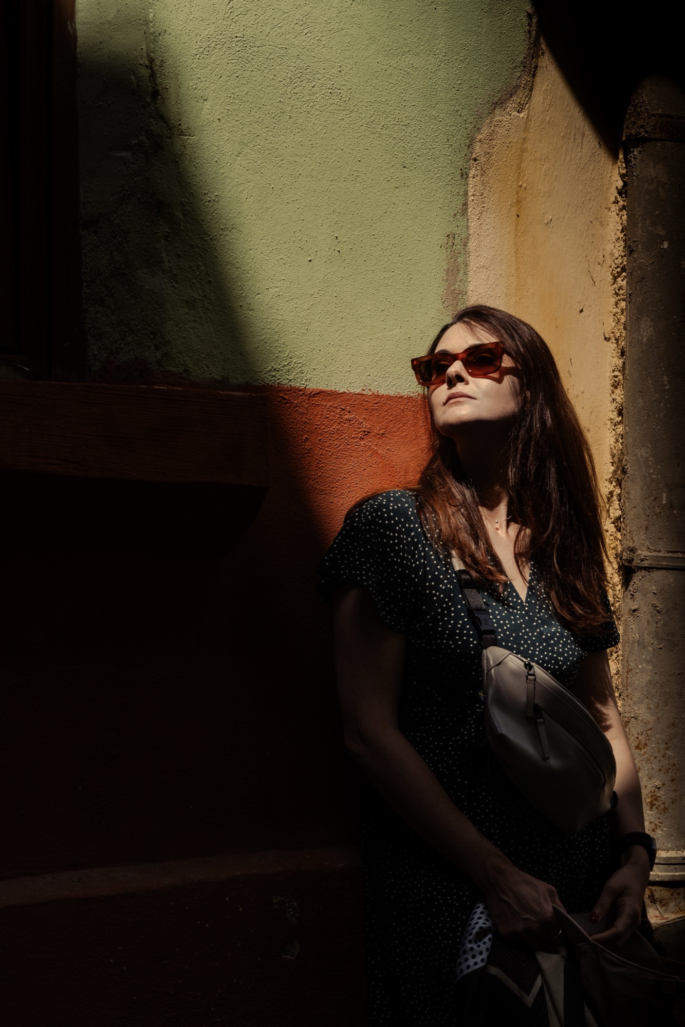 Portrait in raking sun against a green and ochre wall
